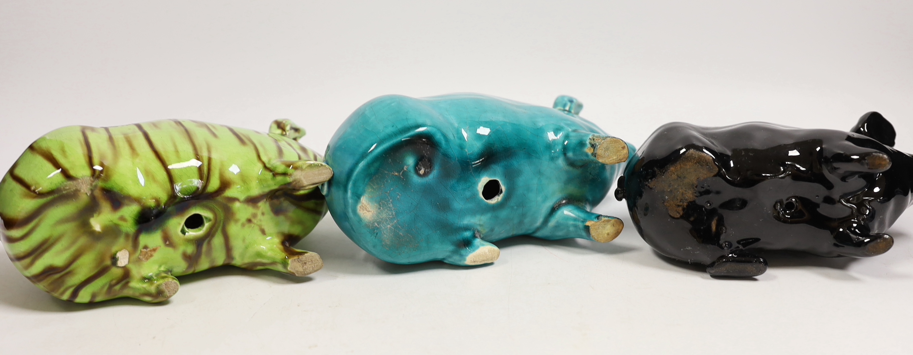 Three Wemyss style pigs in turquoise, pale green / brown and black glazes, one indistinctly marked W.. 15cm